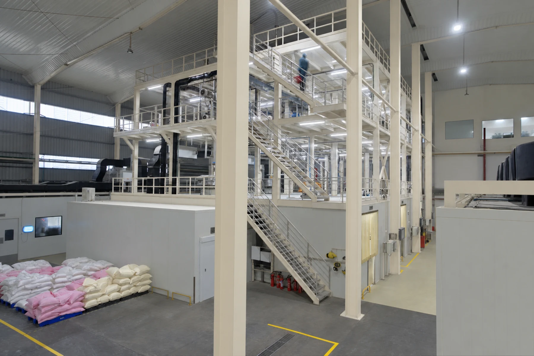 Wide view of the Shree Additives production hall, showing equipment, raised platforms, stored bags and floor markings