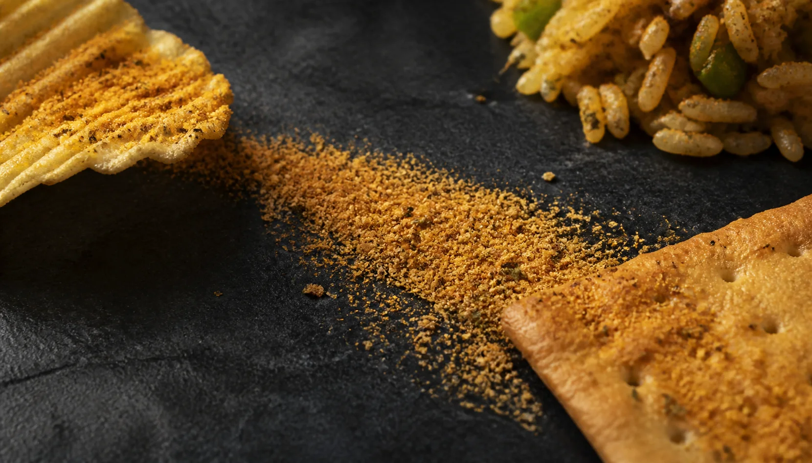 A blended savoury seasoning shown across snack, cracker and prepared-rice textures